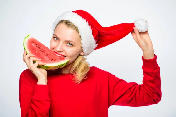 异国情调的圣诞节概念。圣诞女孩吃西瓜。异国情调的寒假。庆祝新年的夏天。女孩戴圣诞老人帽子吃切片西瓜白色背景。圣诞晚会上的夏季盛宴 — 图库照片