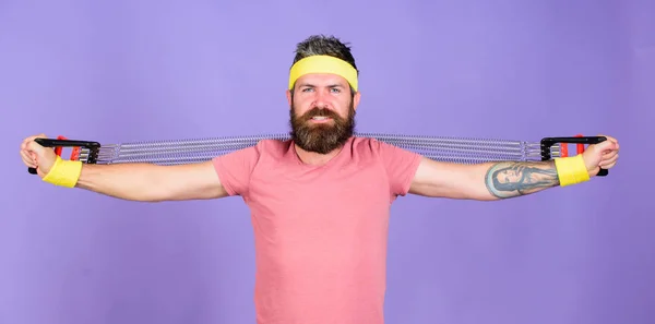 Athletics sport concept. Sportsman wear retro outfit training violet background. Athlete sport instructor. Athlete training with chest expander. Man bearded athlete exercising with expander equipment