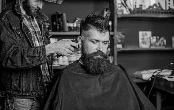 Barber with hair clipper works on hairstyle for bearded guy barbershop background. Hipster client getting haircut. Hipster lifestyle concept. Barber with clipper trimming hair on nape of client — Stock Photo, Image