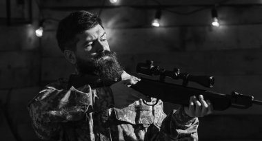 Sakallı adam ahşap iç arka planda kamuflaj elbiseler giyer. Maço gamekeepers evinde sıkı yüzünde. Avcı, av için hazır elinde tabanca ile acımasız hipster. Hakem kavramı