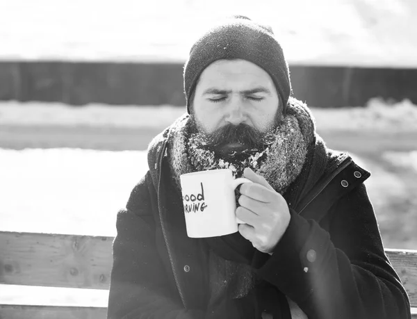 Adam kaşlarını, Günaydın karlı kış günü açık havada doğal adam üzerinde tahta bankta oturan metin ile fincan beyaz Don içecekler sakallı hippi sakal ve bıyık ile kaplı — Stok fotoğraf