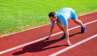 Profesyonel atlet spor ipuçları. Adam atlet runner standı düşük başlangıç pozisyonu stadyum yolu. Zafer için çaba. Runner gitmeye hazır. Yetişkin runner yarış Stadyumu'nda hazırlayın. Yayınlanmaya başlaması nasıl