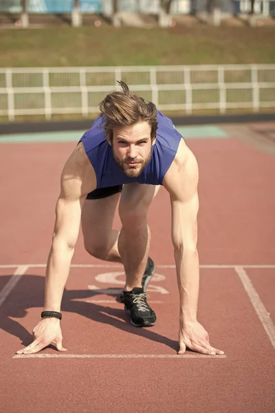 Athletic bearded man with muscular body stretching on running track — Stock Photo, Image