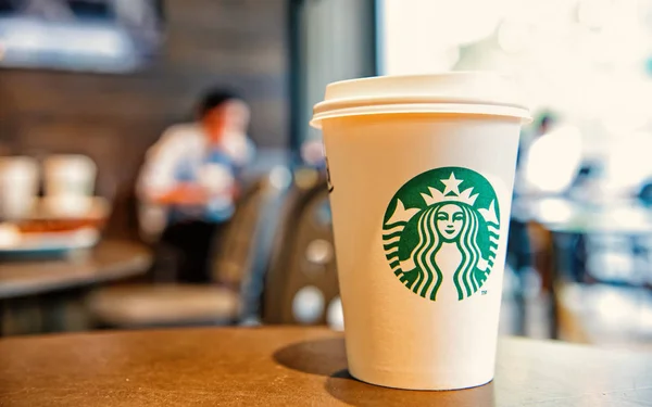 A tall Starbucks coffee cup in starbucks offee shop. — Stock Photo, Image
