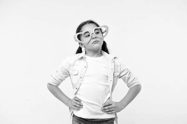 No me importa. Niño tranquilo rostro indiferente fondo amarillo. El chico infeliz no quiere mostrar sentimientos. Las gafas con forma de corazón para niña celebran el día de San Valentín. Chica adorable calma cara corazón gafas — Foto de Stock