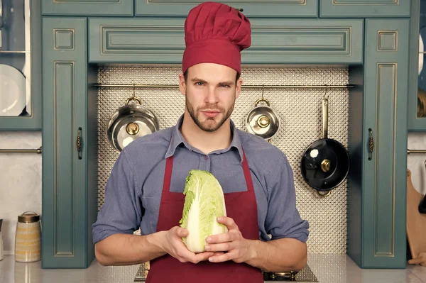 Man chef in red hat, apron hold chinese cabbage