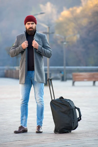 Man bearded hipster travel with big luggage bag wait for taxi bring him to hotel. Travel tips. Traveler with suitcase arrive travel destination. Hipster ready enjoy travel. Looking for accommodation.