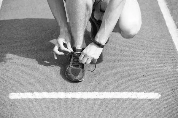 Shoes elite runners wearing marathon. Hands tying shoelaces on sneaker, running surface background. Hands of sportsman with pedometer tying shoelaces on sporty sneaker. Marathon equipment concept — Stock Photo, Image