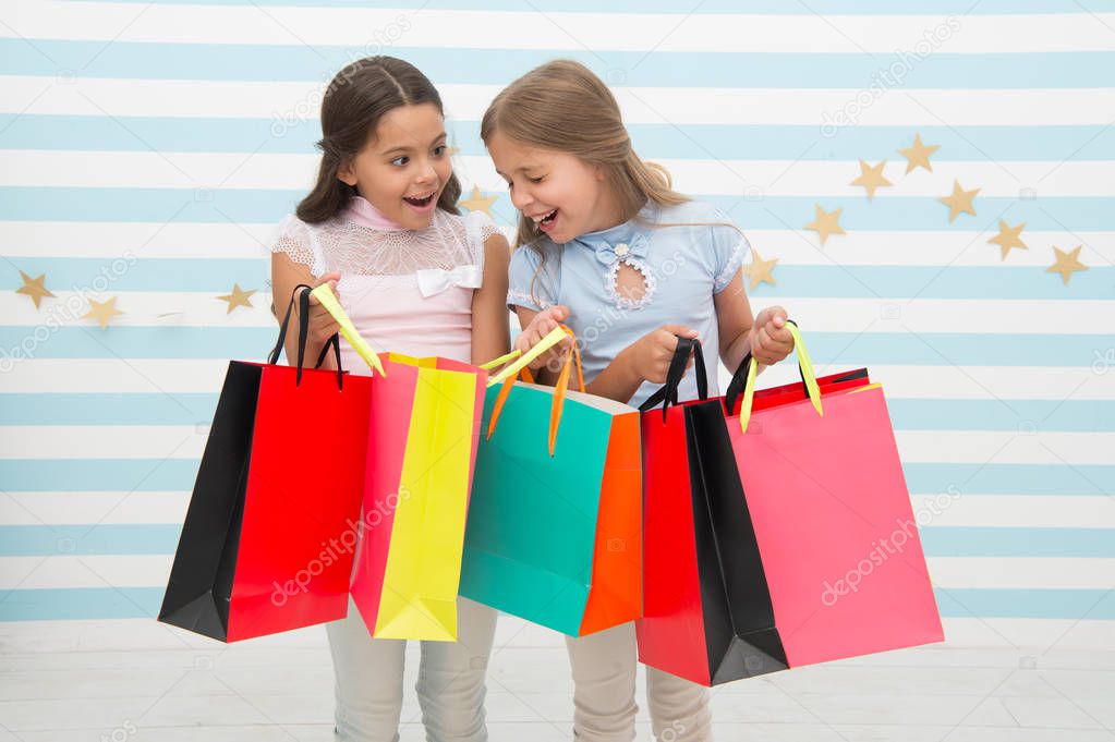 Discount concept. Kids cute girls hold shopping bags. Shopping discount season. Spending great time together. Children satisfied shopping striped background. Obsessed with shopping and clothing malls