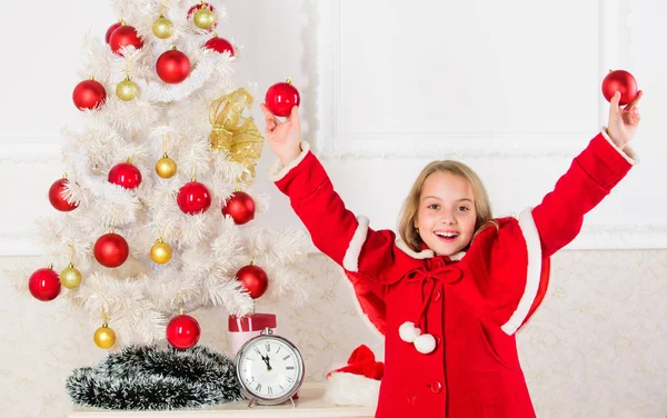 Deixe a criança decorar a árvore de Natal. Parte favorita de decoração. Envolver a criança na decoração. Como decorar a árvore de Natal com a criança. Menina sorridente rosto segurar bolas ornamentos branco interior fundo — Fotografia de Stock