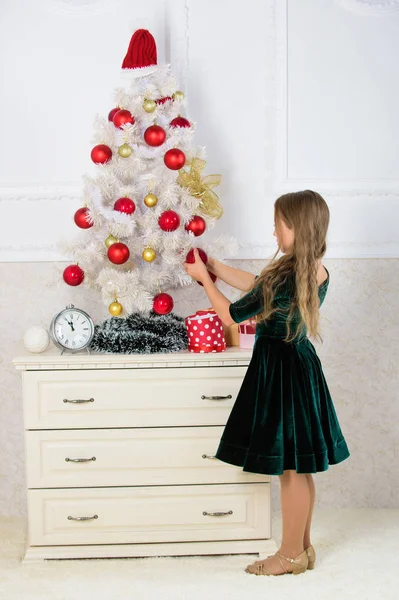 Dzieci można rozjaśnić choinki, tworząc własne ozdoby. Dziewczyna świętować Boże Narodzenie. Dziecko umieścić christmas ornament piłka na sztuczne biały drzewo. Najlepsze świąteczne dekorowanie pomysły dla dzieci Pokój — Zdjęcie stockowe