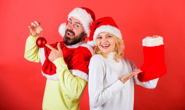 Onay içeriğini Noel çorap hediye aldı. Çift neşeli yüzü Hediyelik Noel çorap içinde kontrol. Noel hediye kavramı. Kadın ve sakallı adam santa şapka hediye kırmızı arka plan bekliyor