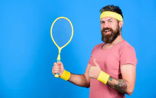 Athlete hold tennis racket in hand on blue background. Tennis sport and entertainment. Tennis club concept. Man bearded hipster wear old school sport outfit with bandages. Tennis player retro fashion