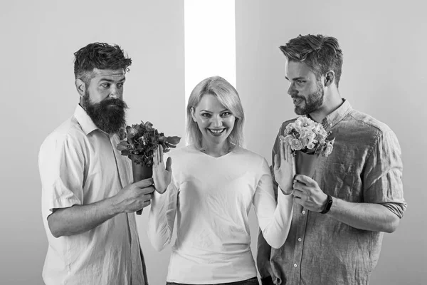 Mannen concurrenten met boeketten bloemen proberen meisje veroveren. Meisje glimlachend verwerpen geschenken. Feminisme concept. Vrouw die lacht verwerpen beide mannelijke partners. Uit de betrekkingen. Populaire meisje veel mannen aandacht krijgen — Stockfoto