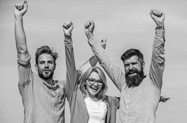 Company reached top. Men with beard in formal shirts and blonde in eyeglasses as successful team. Company of three happy colleagues or partners celebrating success, sky background. Success concept