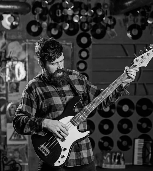 Bassist concept. Man s holds bass guitar, play music in club atmosphere background. Musician, artist play electric guitar musical instrument. Fingers clamp strings on bass guitar neck — Stock Photo, Image