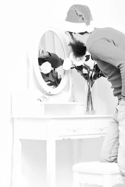 El tipo se inclina hacia el espejo con flores en jarrón. — Foto de Stock