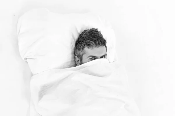Guy hides face under blanket. Lazy and laziness