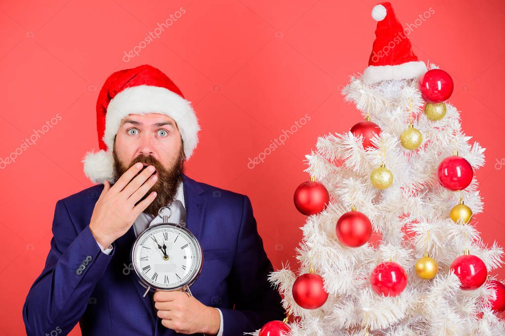 Counting time till christmas. How much time left. Keep track of time. Time to celebrate. Businessman join christmas celebration. Man bearded wear suit and santa hat hold clock. Last minute deals.
