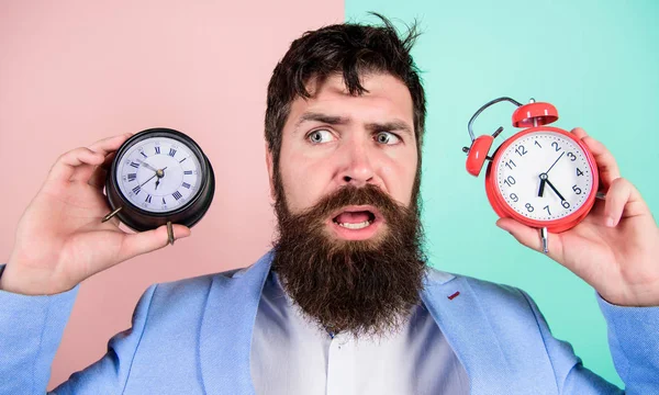 L'évolution des fuseaux horaires affecte la santé. Fuseau horaire. Est-ce que changer d'horloge gâche votre santé. Homme barbu hipster tenir deux horloges différentes. Guy visage perplexe non rasé ayant des problèmes avec le changement de temps — Photo