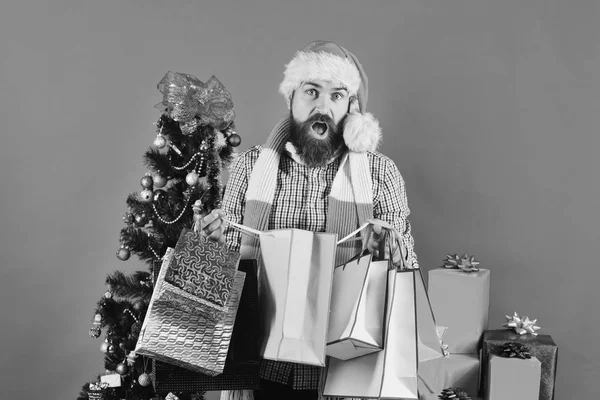Guy in red hat with shopping bags full of presents. — Stock Photo, Image