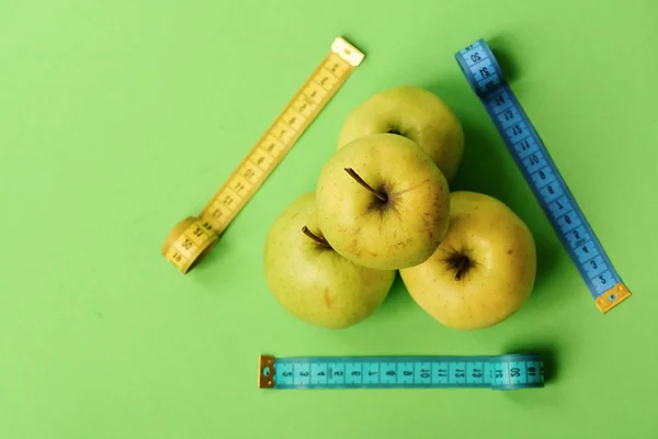 Äpplen nära mäta tejp rullar på grön bakgrund, ovanifrån — Stockfoto