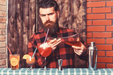 Sakallı ve sert yüzlü barmen kokteyl yapar..