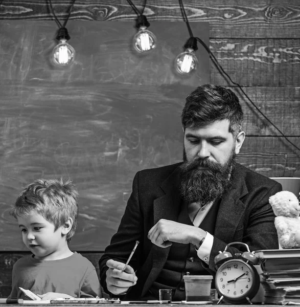 Child and teacher on busy faces painting, drawing. Teacher with beard, father and little son in classroom while drawing, creating, chalkboard on background. Arts lesson concept — Stock Photo, Image