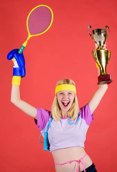 Sport equipment store. Sport shop assortment. Girl cheerful successful modern woman hold golden goblet of sport champion and equipment red background. Sport for every day. How to stay fit forever