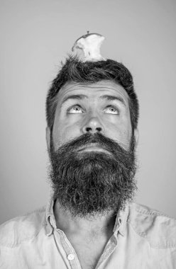 Canlı hedef kavramı. Adam yakışıklı hipster uzun sakal neredeyse kafasına elma güdük hedef olarak yem. Hipster sürpriz elma güdük hedef üzerinde kafa mavi arka plan, yüz kadar yakın. Kilo kaybı gol