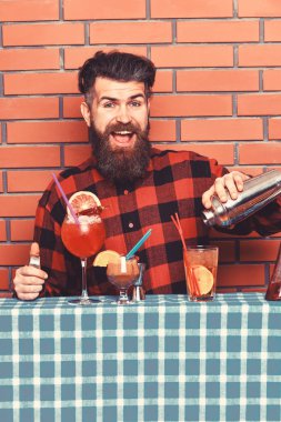 Adam shaker tuğla duvar arka plan üzerinde tutar. Barmen sakal ve mutlu yüz ile kokteyl yapar. Barmen veya hipster buz ve saman ile taze içecek yapar. Şık barmen kavramı