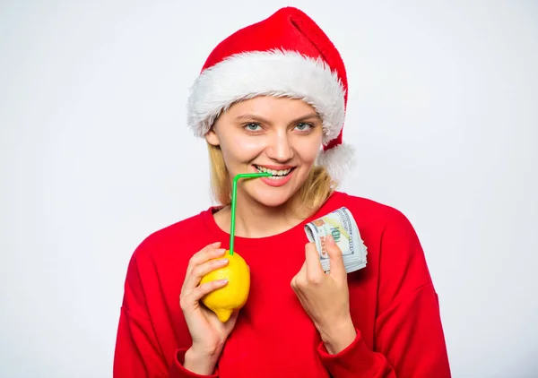 妇女柠檬百万富翁。柠檬钱的概念。女孩圣诞老人帽子喝果汁柠檬稻草, 而举行一堆钱。财富和繁荣的象征。圣诞祝福。富有的女孩与柠檬和金钱 — 图库照片