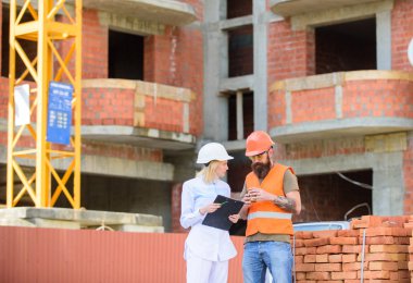 İnşaat istemcileri ve inşaat sektöründe katılımcılar arasındaki ilişkiler. Kadın mühendis ve Oluşturucu inşaat alanında iletişim. Planı tartışıyor. İnşaat ekibi iletişim kavramı