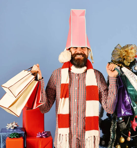 Santa with colorful packets near decorated fir tree.