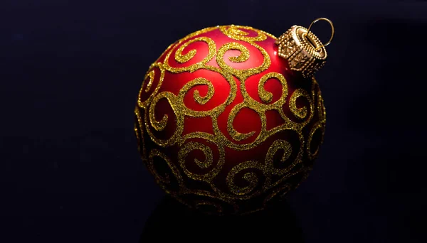 Christmas ornament single red ball on black background. Christmas ornament concept. Elegant and luxury christmas decor close up. Ball ornament on black surface. Pick decor for christmas tree