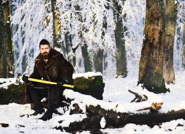 Kürk ceket adam, sarı balta tutar. Maço sakallı