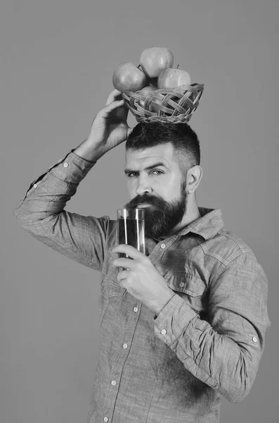 Farmer with serious face holds juice and apples on head