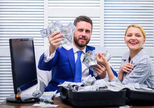 Handsome man happy and surprised with money hundreds dollars in case. Young businessman looking at money scattered on table. Profit and richness concept.