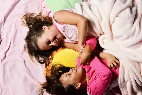 Écolières en pyjama rose se vautrer sur des oreillers colorés, vue sur le dessus — Photo