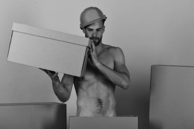 Elinde karton kutuyla çırılçıplak duran kasklı adam. 