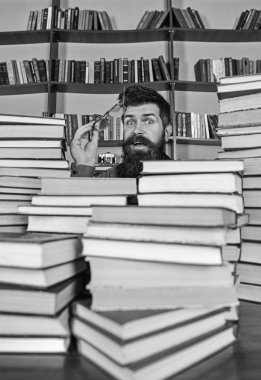 Öğretmen ya da öğrenci sakallı gözlük takmaz, defocused kitaplar ile masada oturur. Bilimsel araştırma kavramı. Adam kazık kitap Kütüphane, kitap rafı arka plan üzerinde arasında sürpriz yüzünde