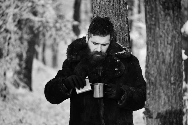 El hombre con abrigo de piel sostiene el frasco y la taza . — Foto de Stock