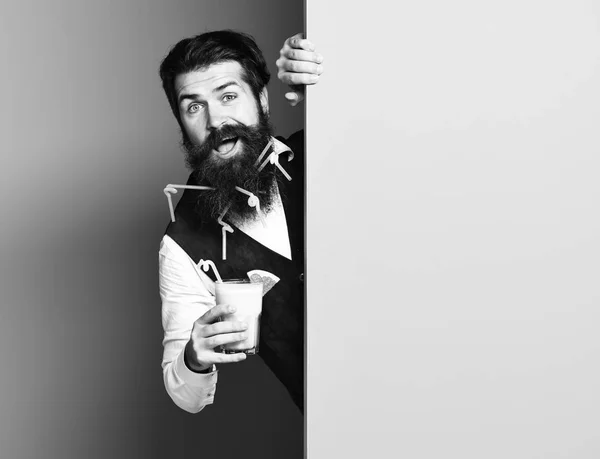 Przystojny, brodaty mężczyzna z długą brodę i wąsy ma stylowe włosy na uśmiechniętą twarz, trzymając szklankę napoju alkoholowego w vintage zamszu skórzana kamizelka na tle niebieski zielony studio, kopia spac — Zdjęcie stockowe