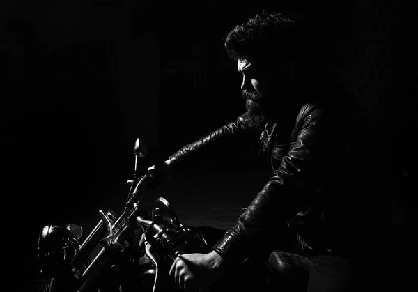 Concept de masculinité. Homme à barbe, motard veste en cuir assis sur moto dans l'obscurité, fond noir. Macho, motard brutal en veste en cuir à moto de nuit, espace de copie — Photo