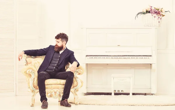 Macho atractivo y elegante en cara seria y expresión reflexiva. Concepto de estilo de vida Elite. Hombre con barba y bigote con traje clásico, se sienta en un sillón a la antigua en el interior de lujo —  Fotos de Stock