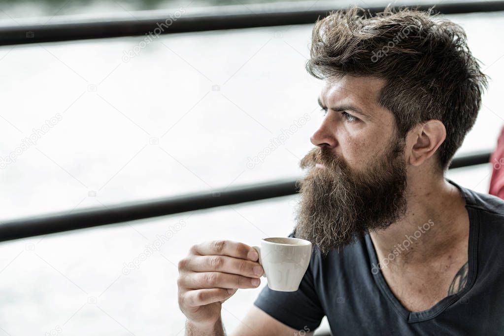 Bearded guy relaxing at cafe terrace. Guy relaxing with espresso coffee. Coffee break concept. Hipster drinking coffee outdoor. Caffeine recharge. Man with beard and mustache and cup of coffee