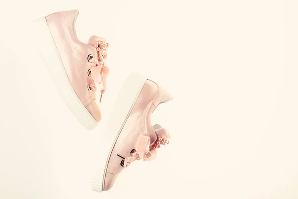 Обувь для девочек и женщин, украшенных жемчужинами. Симпатичные туфли изолированы на белом фоне, вид сверху, копировальное пространство. Модные кроссовки. Пара бледно-розовых женских кроссовок с бархатными лентами — стоковое фото