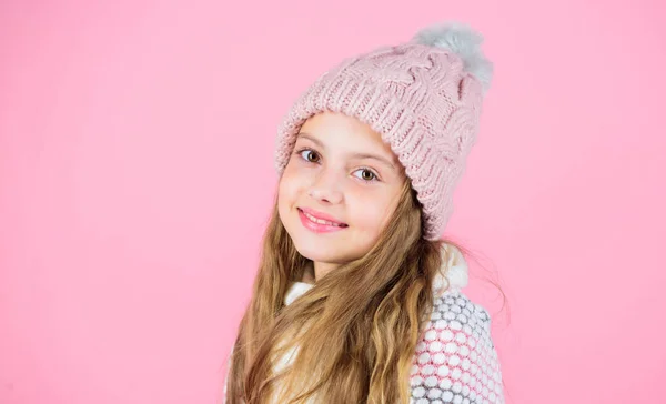 Prevent winter hair damage. Winter hair care tips you should definitely follow. Winter time train yourself to go longer between washes. Child long hair smiling. Girl wear knitted hat pink background