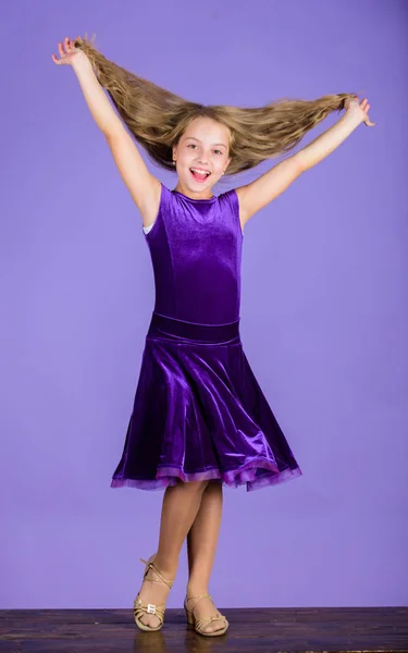 How to make tidy hairstyle for kid. Things you need know about ballroom dance hairstyle. Ballroom latin dance hairstyles. Kid girl with long hair wear dress on violet background. Hairstyle for dancer