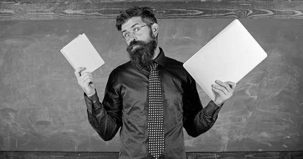 Fique moderno com a tecnologia. Professor hipster barbudo detém livro e laptop. As tecnologias modernas beneficiam. Digital contra papel. Escolha o método correto de ensino. Professor escolhendo abordagem de ensino moderno — Fotografia de Stock